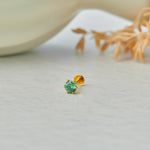 Close up of emerald green stone gold nose pin on neutral background