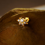 Close-up of a gold nose pin with a curved loop accent and a cluster of sparkling clear stones, set against a dark velvet backdrop