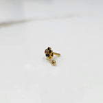 Side view of gold ring featuring black gemstone cluster with drop charm accent