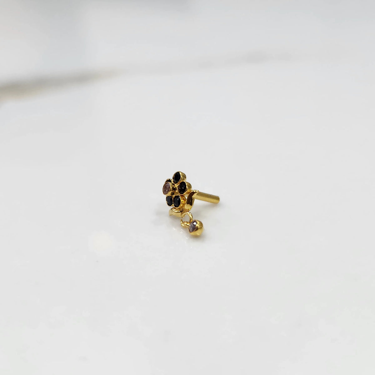 Side view of gold ring featuring black gemstone cluster with drop charm accent