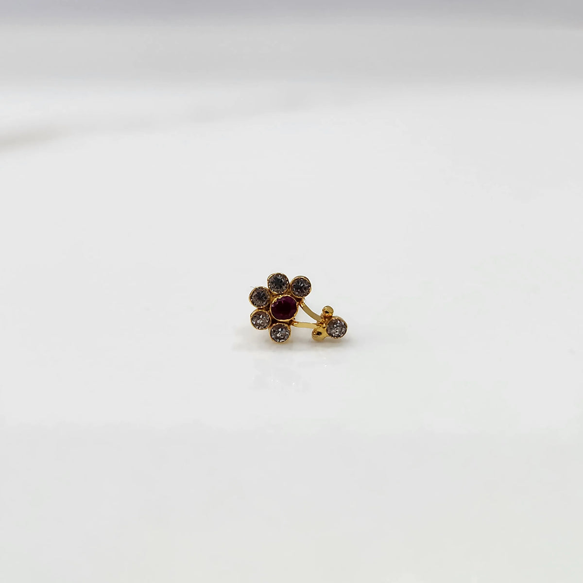 Antique-style gold ring with clear-toned stones, ruby center, plus hanging accent