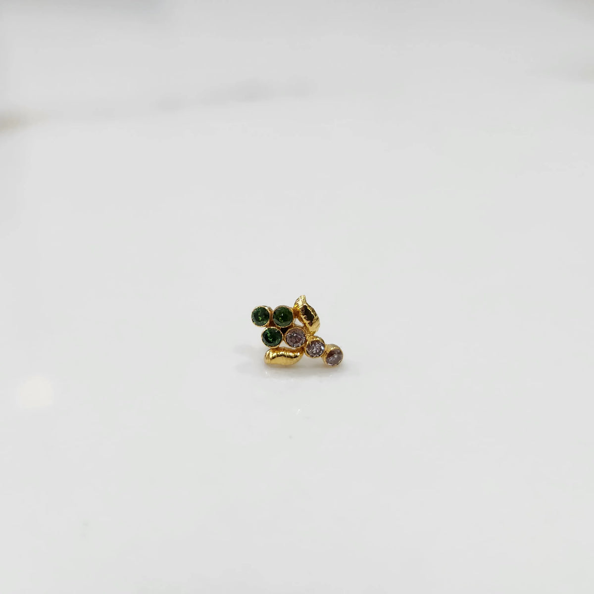 Antique-style gold ring with green and purple-toned stones in leaf-charm pattern
