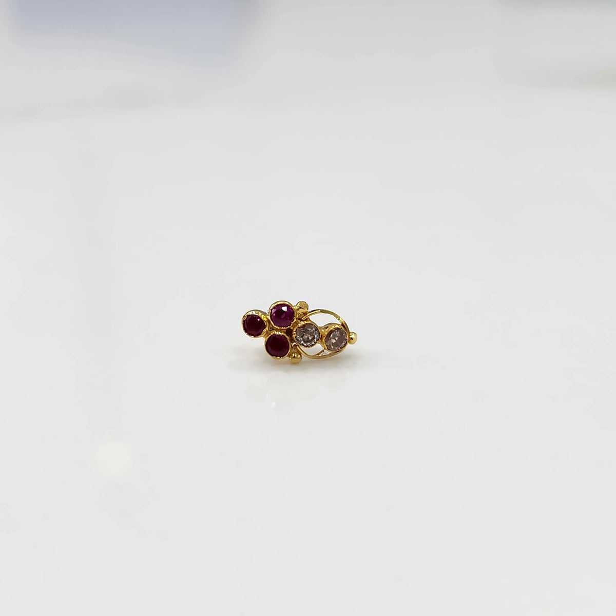 Antique-style gold ring featuring clustered red and clear-toned gemstones
