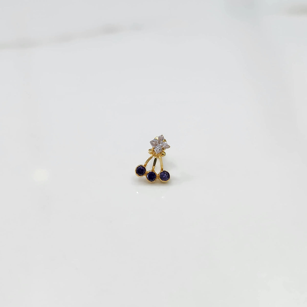 Antique-style gold ring featuring a square stone and hanging purple gems