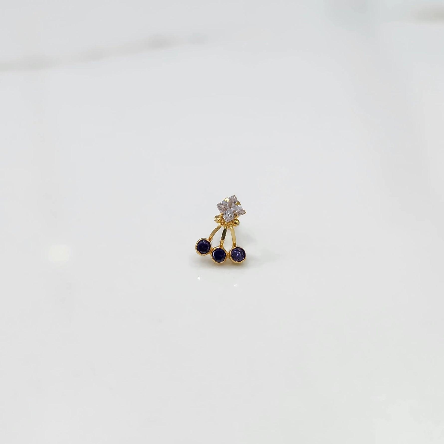 Antique-style gold ring featuring a square stone and hanging purple gems