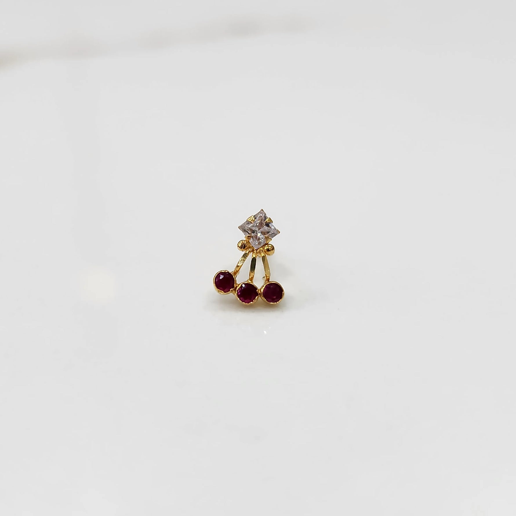Gold ring with clear center stone and red gemstone accents