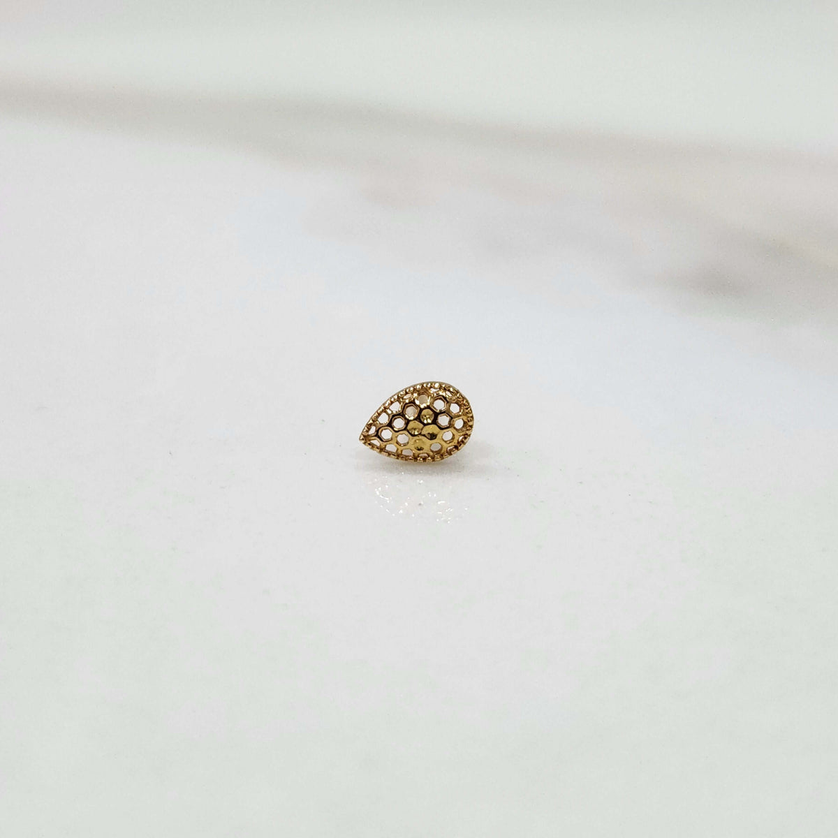 Side view of 18k teardrop gold nose pin design featuring smooth finish and sophisticated detailing