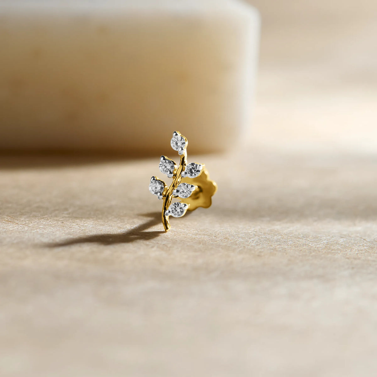 Leaf-shaped diamond stud earring in 14k gold with vine design