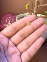 Round gold nose pin with engraved leaf pattern, held in hand
