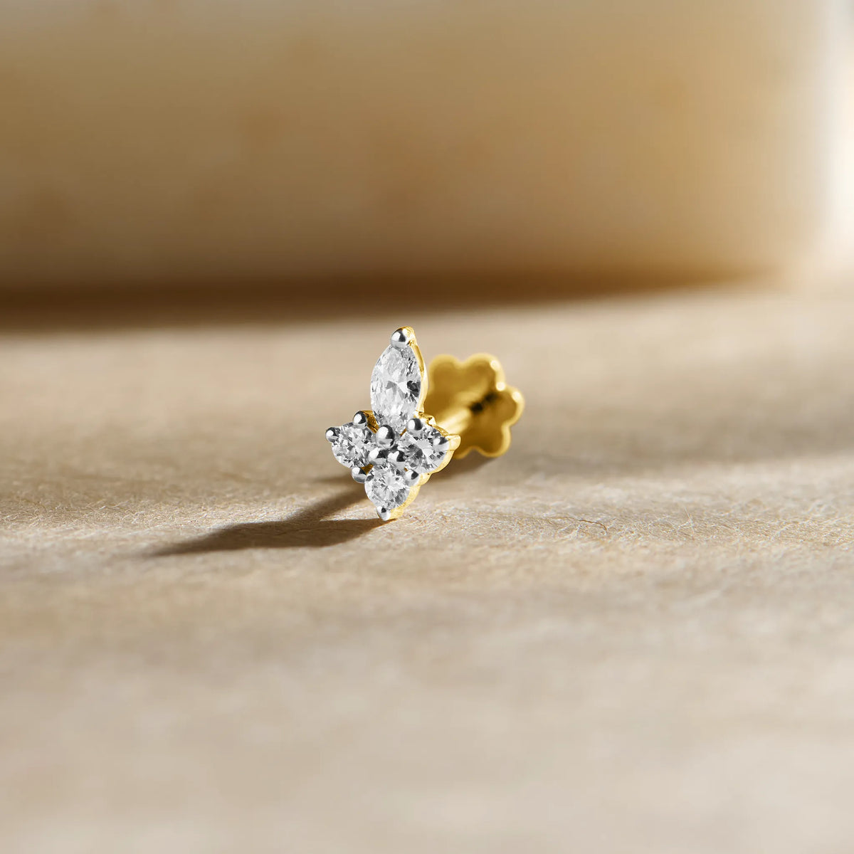 Three-stone diamond stud earring with marquise-cut center diamond in gold