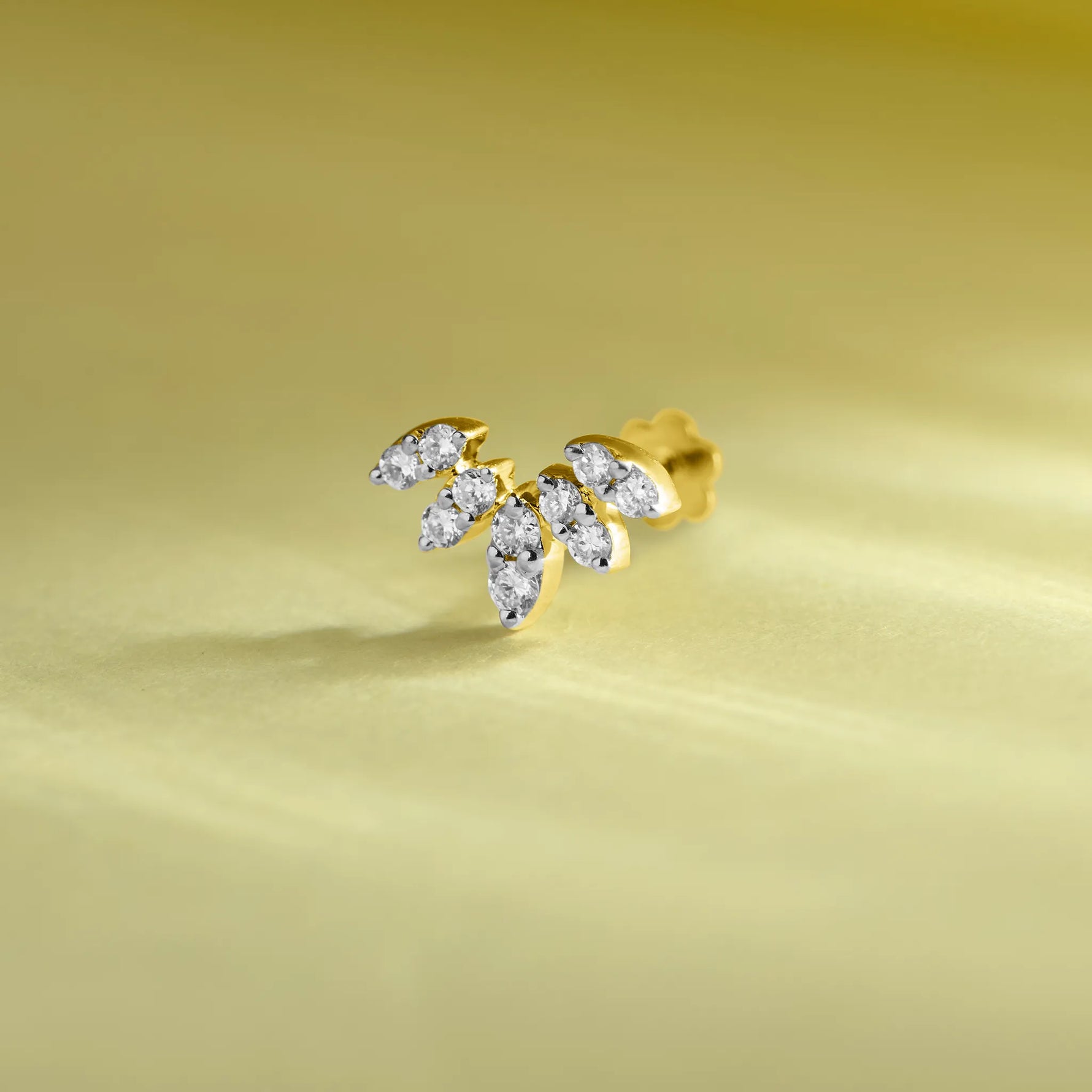 Fancy gold nose pin with leaf-shaped diamonds on pastel background