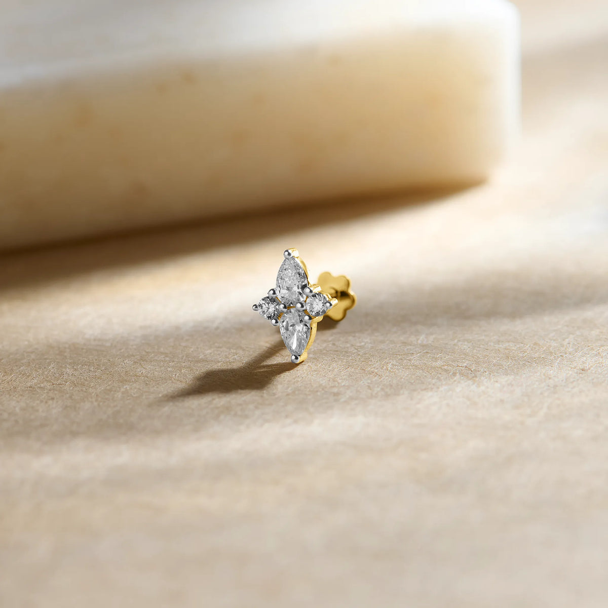 Gold pin nose with marquise diamond floral design on soft beige background