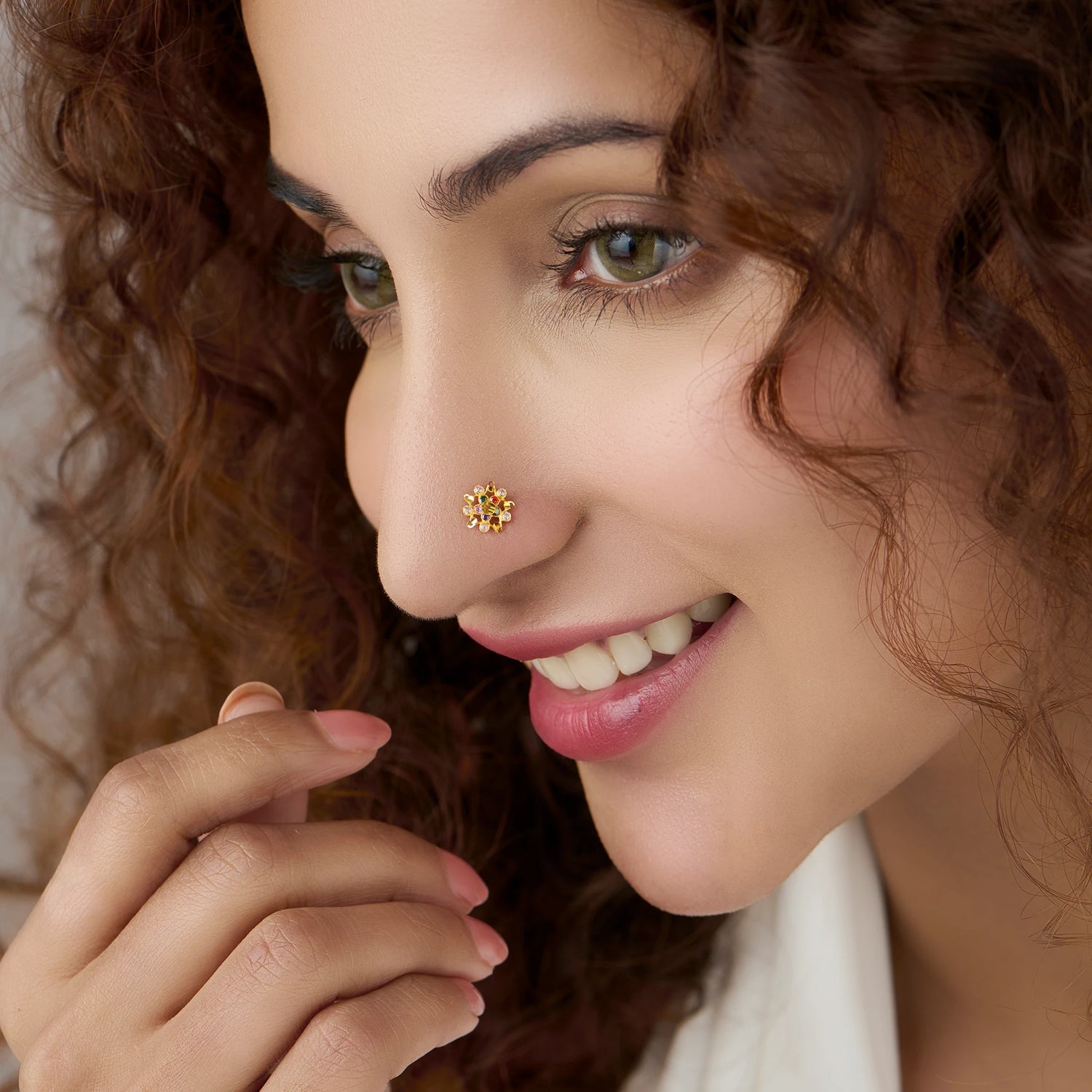 Woman wearing matte gold flower-shaped nose pin, close-up