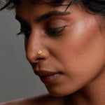 Close-up of matte gold trefoil-shaped nose pin on woman's nose