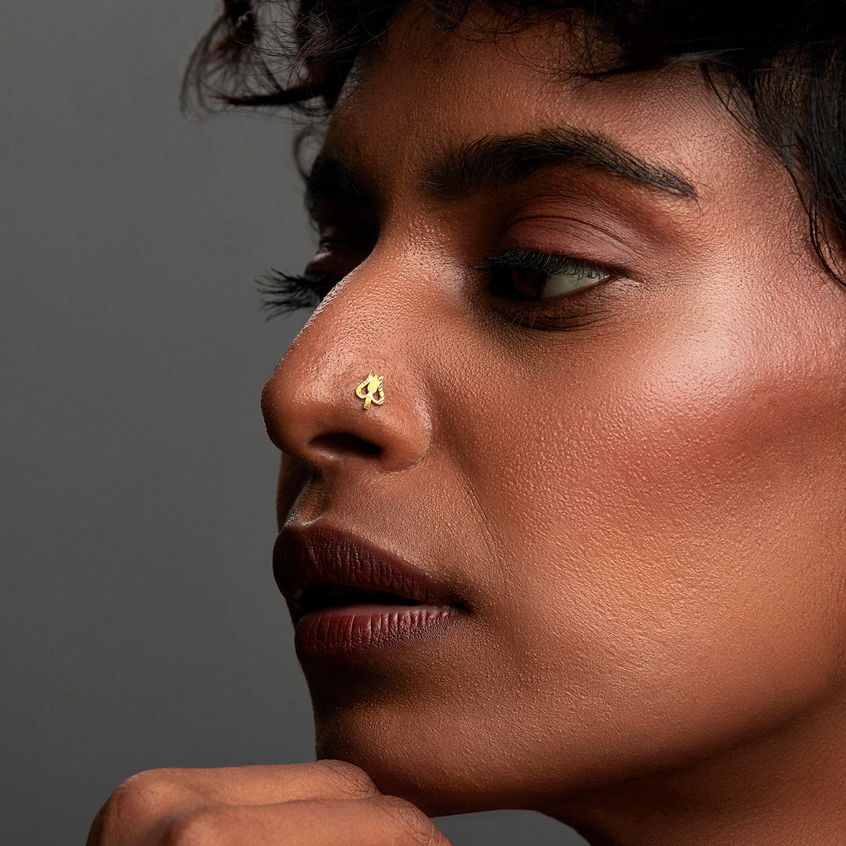 Side profile of woman wearing minimal open-design gold nose ring