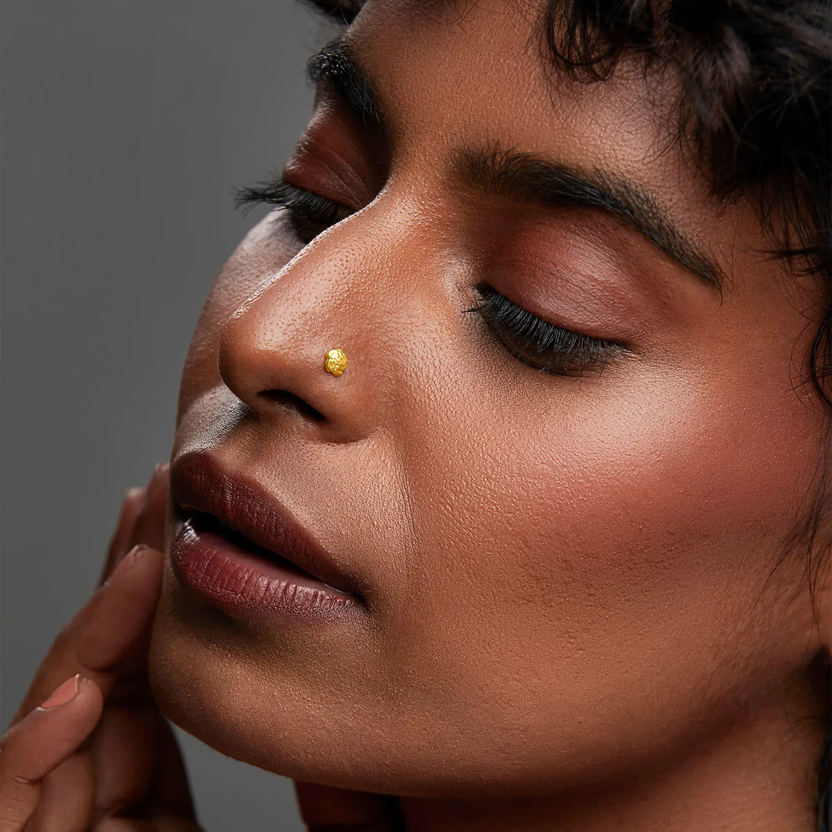 Woman wearing a small gold nose stud, close-up lifestyle photo