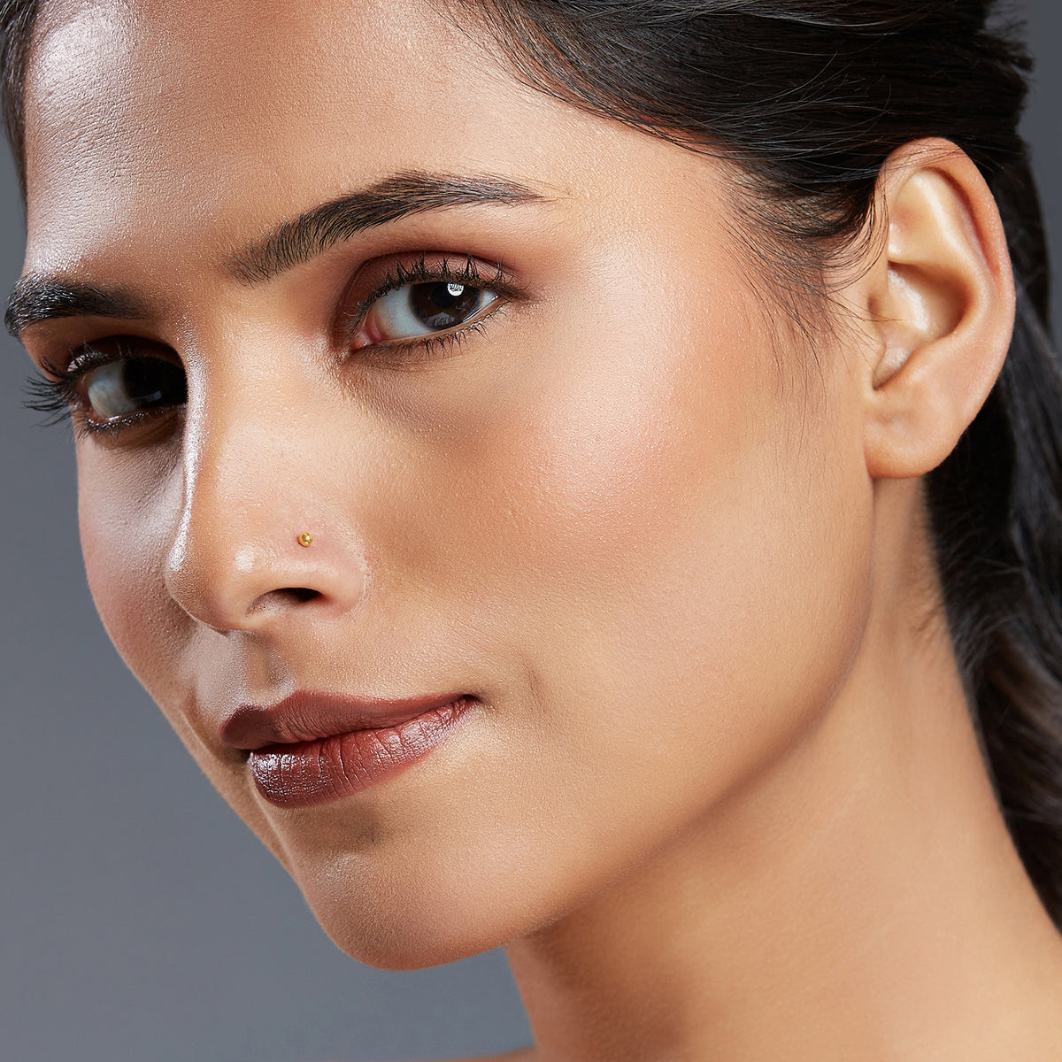 Woman wearing minimal single stone gold nose stud close-up