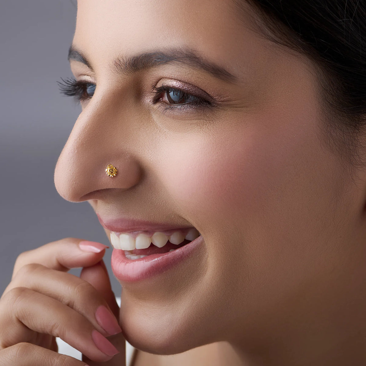 Close-up of a smiling woman wearing a small gold star flower nose pin