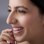 Close-up of a smiling woman wearing a small gold star flower nose pin