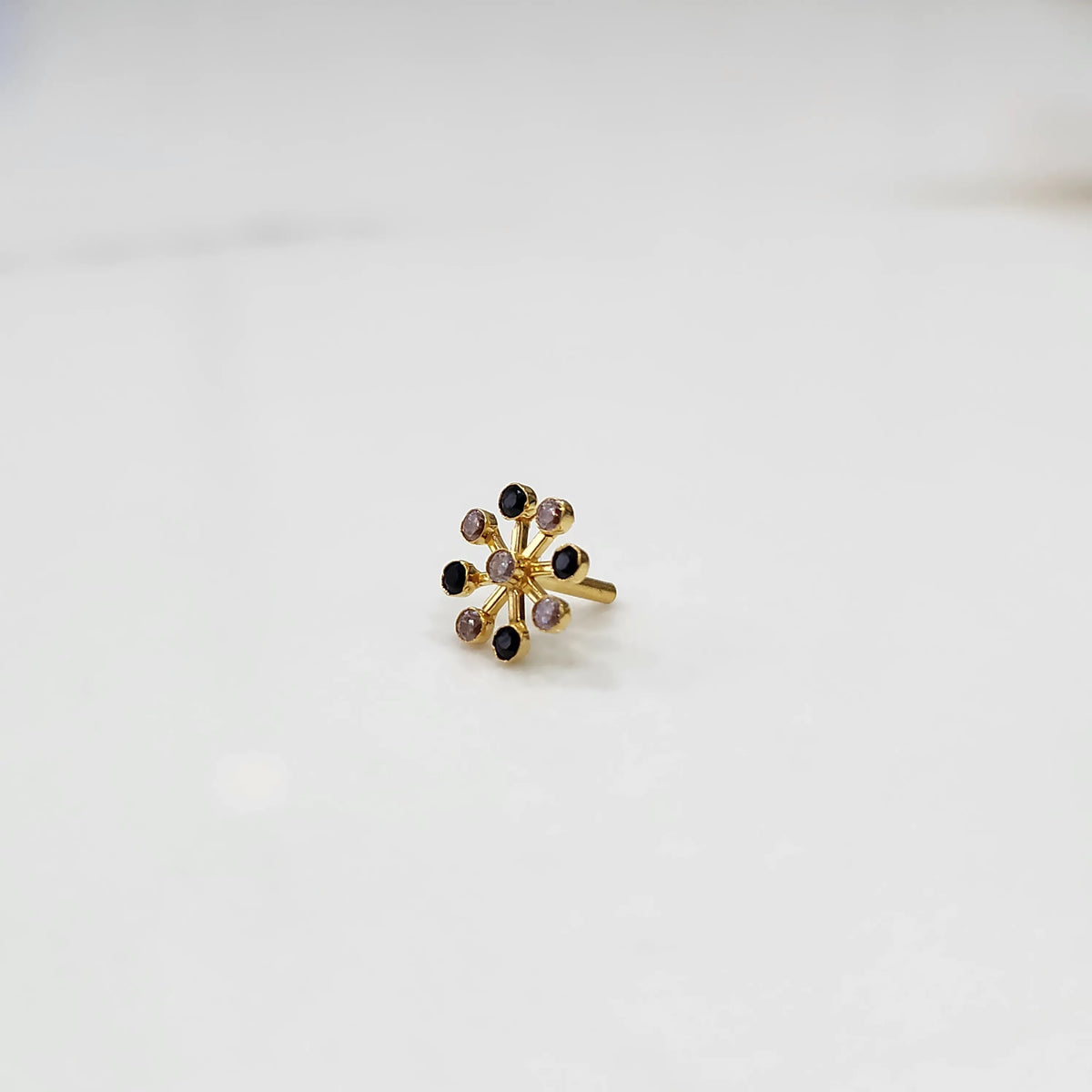 Elegant gold stud with eight-stone black and clear gem design, product close-up