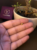 Gold nose pin with multicolor stone flower pattern, held in hand