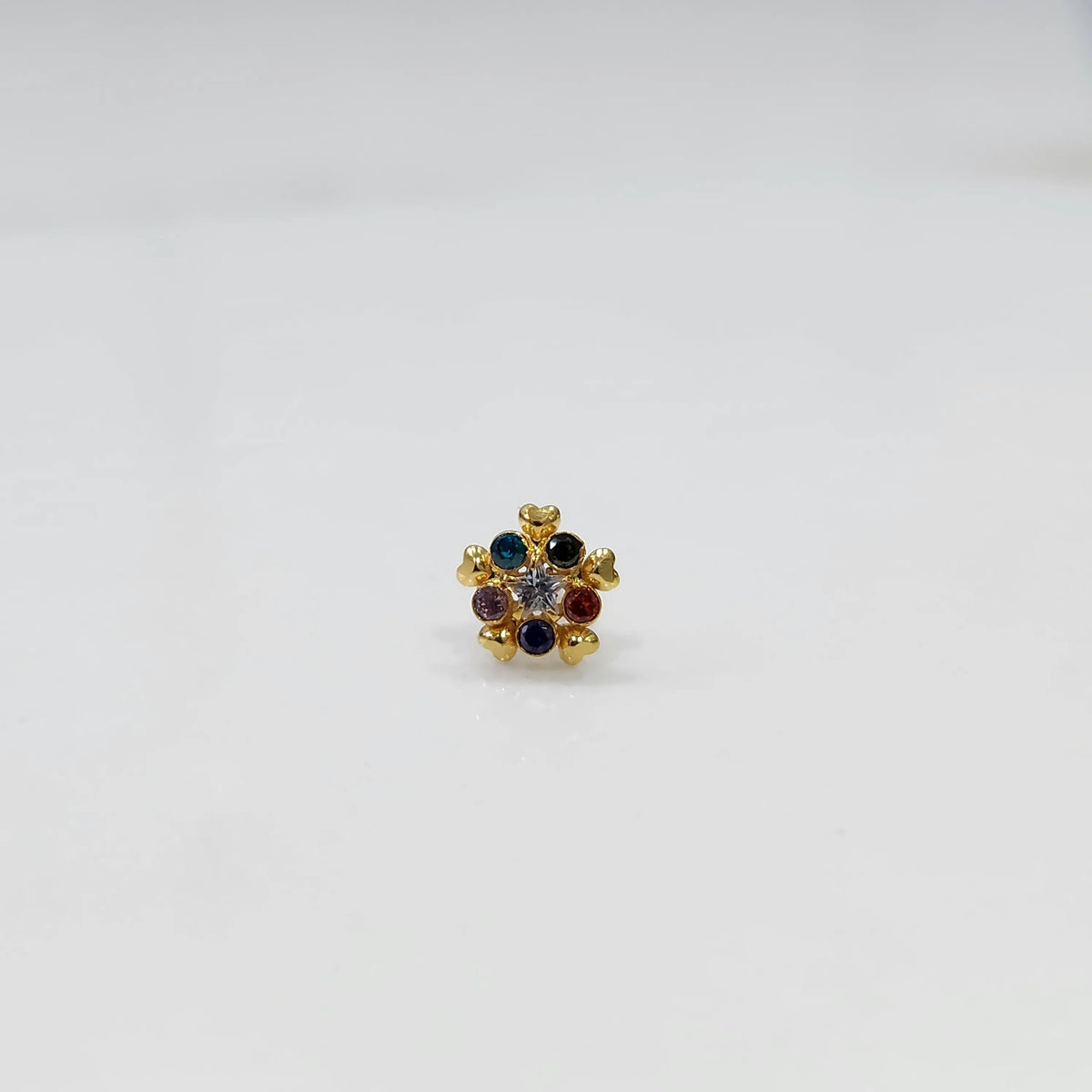 Close-up of a navratna-style nose pin with red, blue, and clear stones