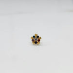 Close-up of a navratna-style nose pin with red, blue, and clear stones