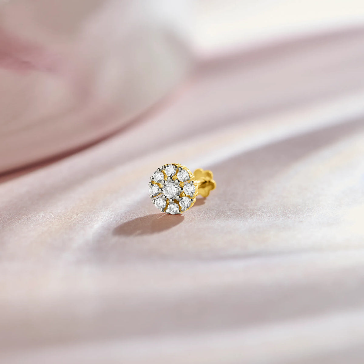 Floral diamond nose pin design from kerala in gold with cluster setting on soft pink background