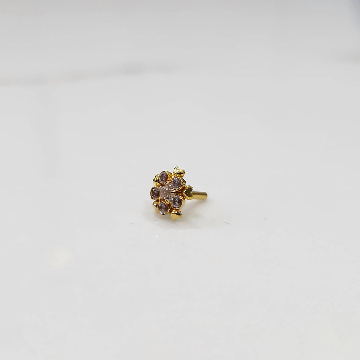 Clear CZ flower cluster nose stud with gold heart setting, jewelry photography