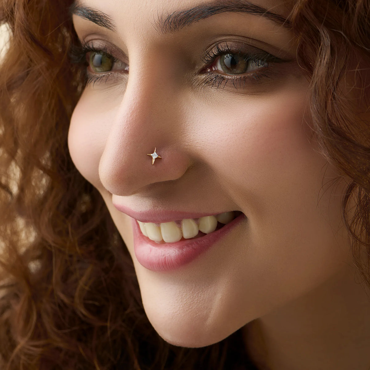 Sparkle star diamond nose stud worn by a smiling woman, close-up beauty shot