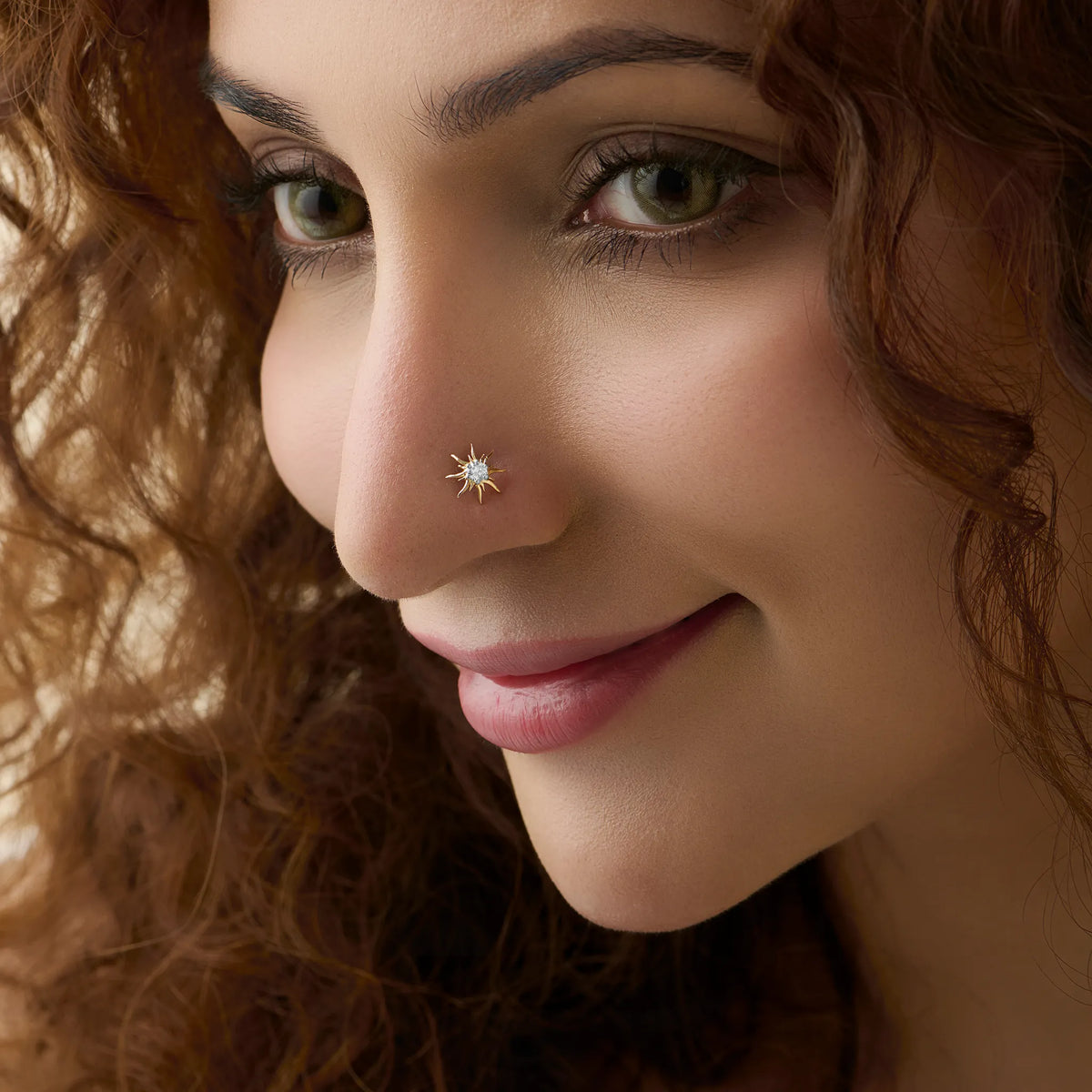 North-star diamond nose stud worn by a smiling woman, close-up beauty shot