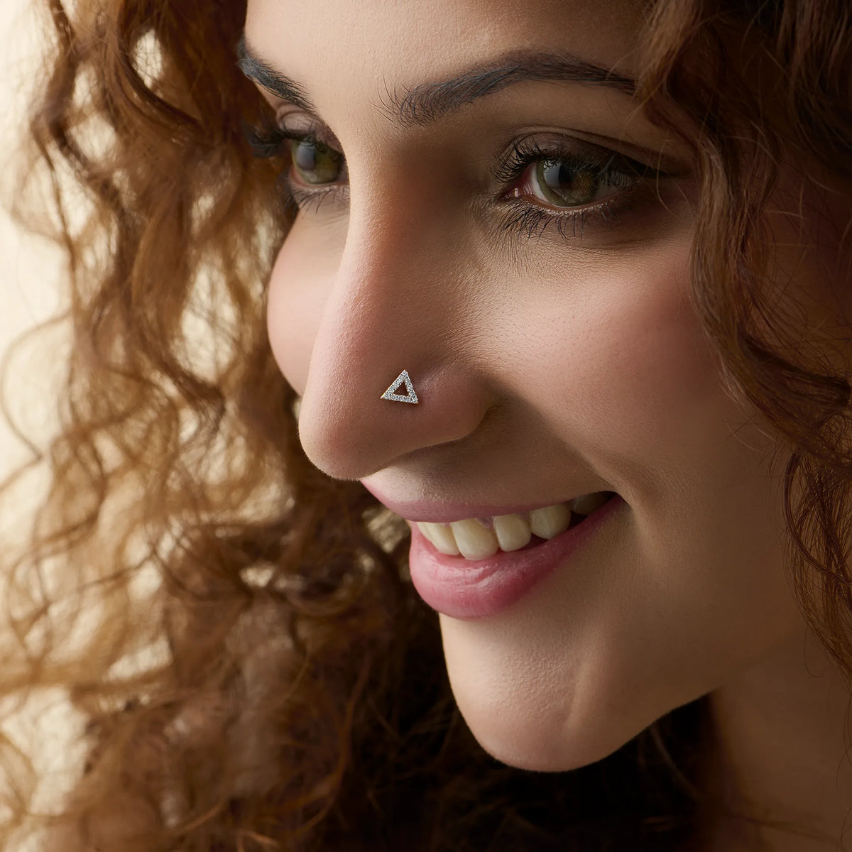 Woman wearing fancy gold triangle nose pin close-up portrait