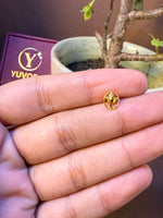 Oval-shaped gold nose pin with engraved paisley motif inside a border, held in hand
