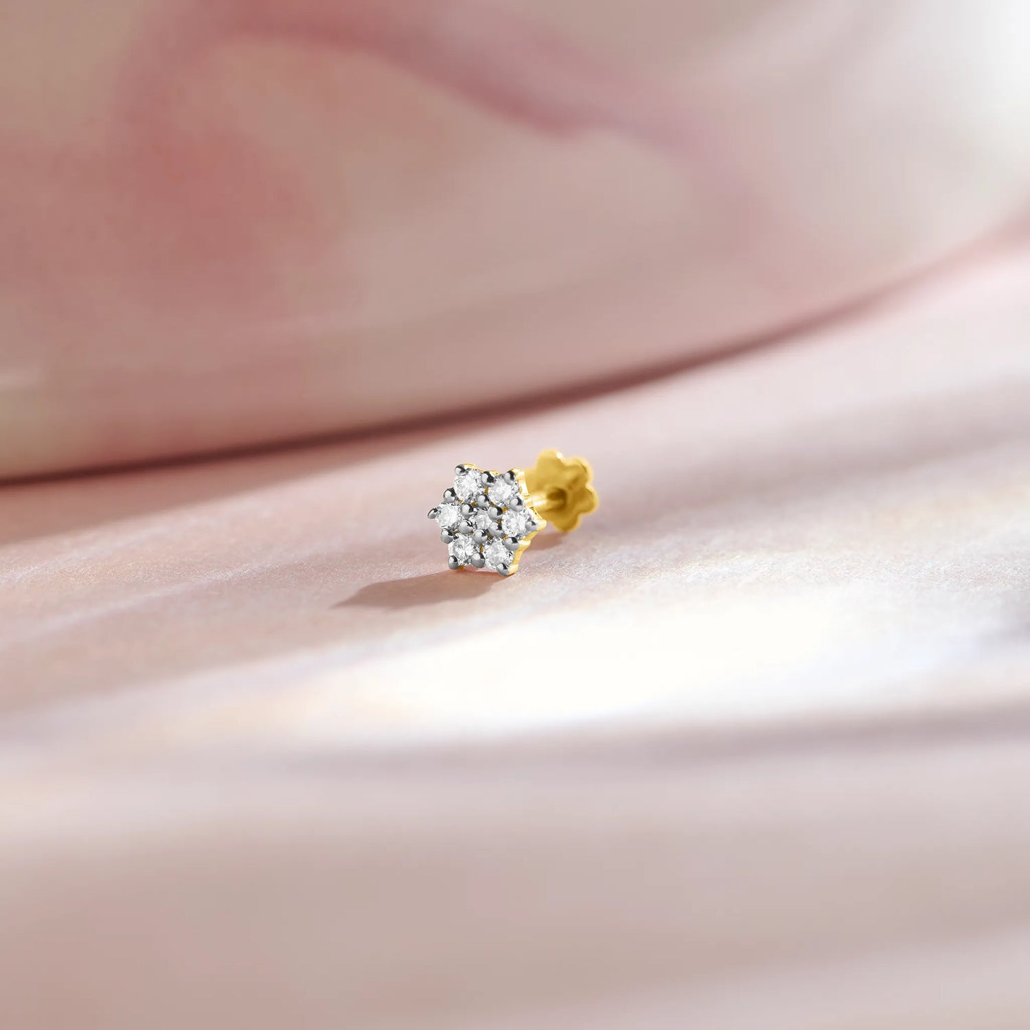 Stone Gold Nose Pin in gold with a sparkling white solitaire stone placed on soft pink satin background