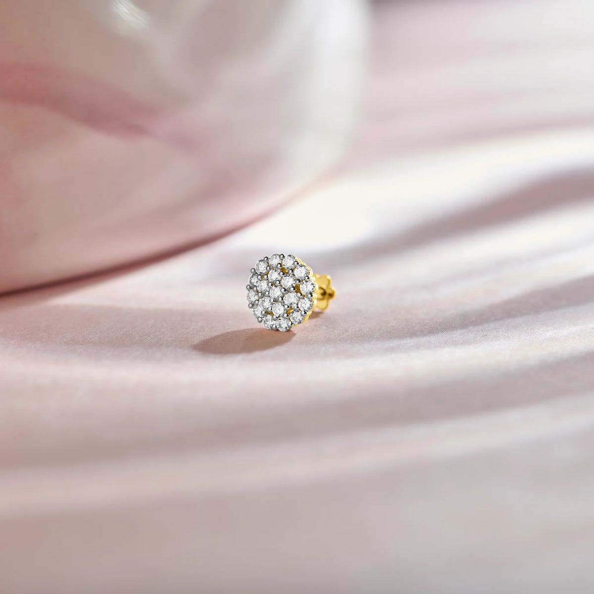 Product shot of a gold nose stud with a round dome-shaped gemstone cluster