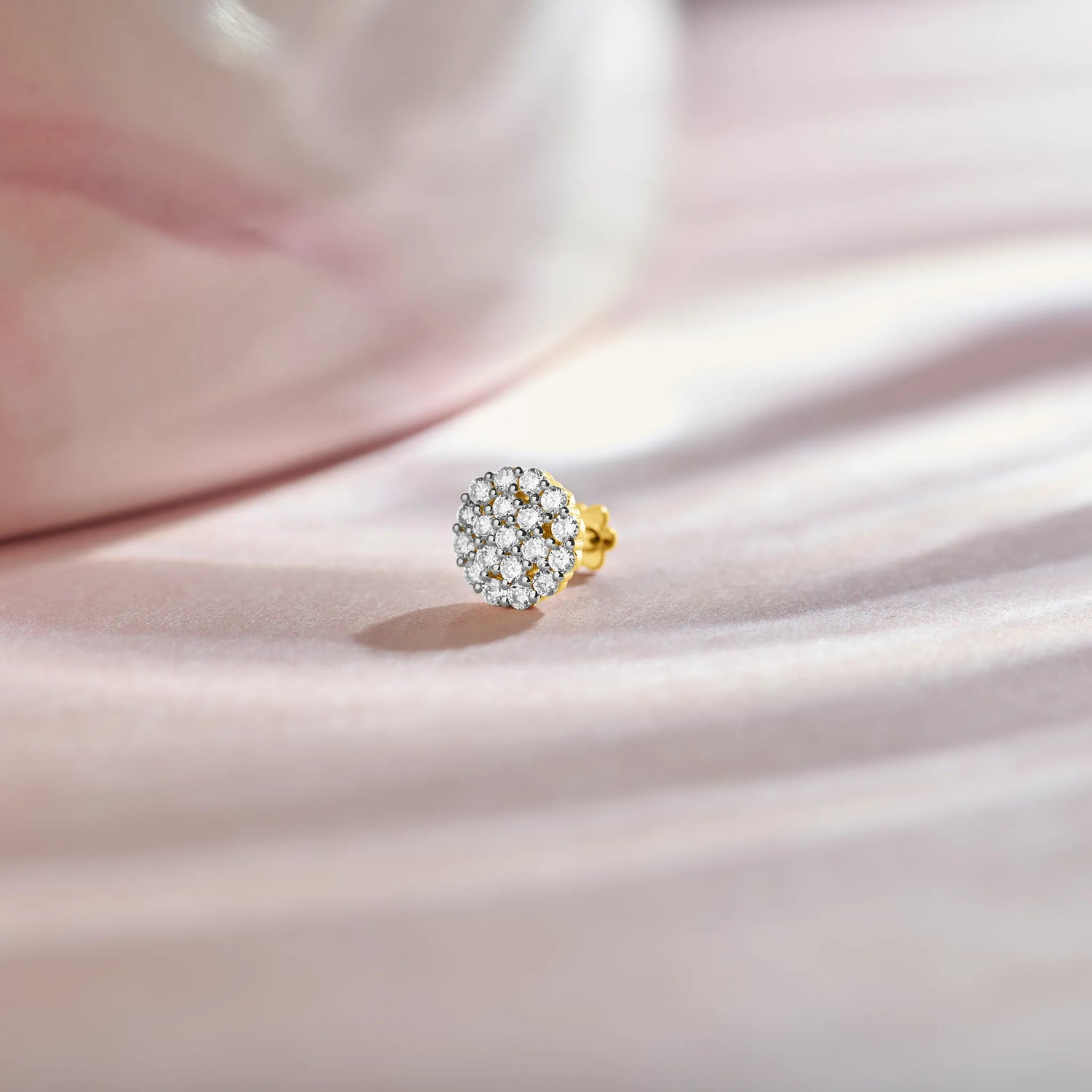 Product shot of a gold nose stud with a round dome-shaped gemstone cluster