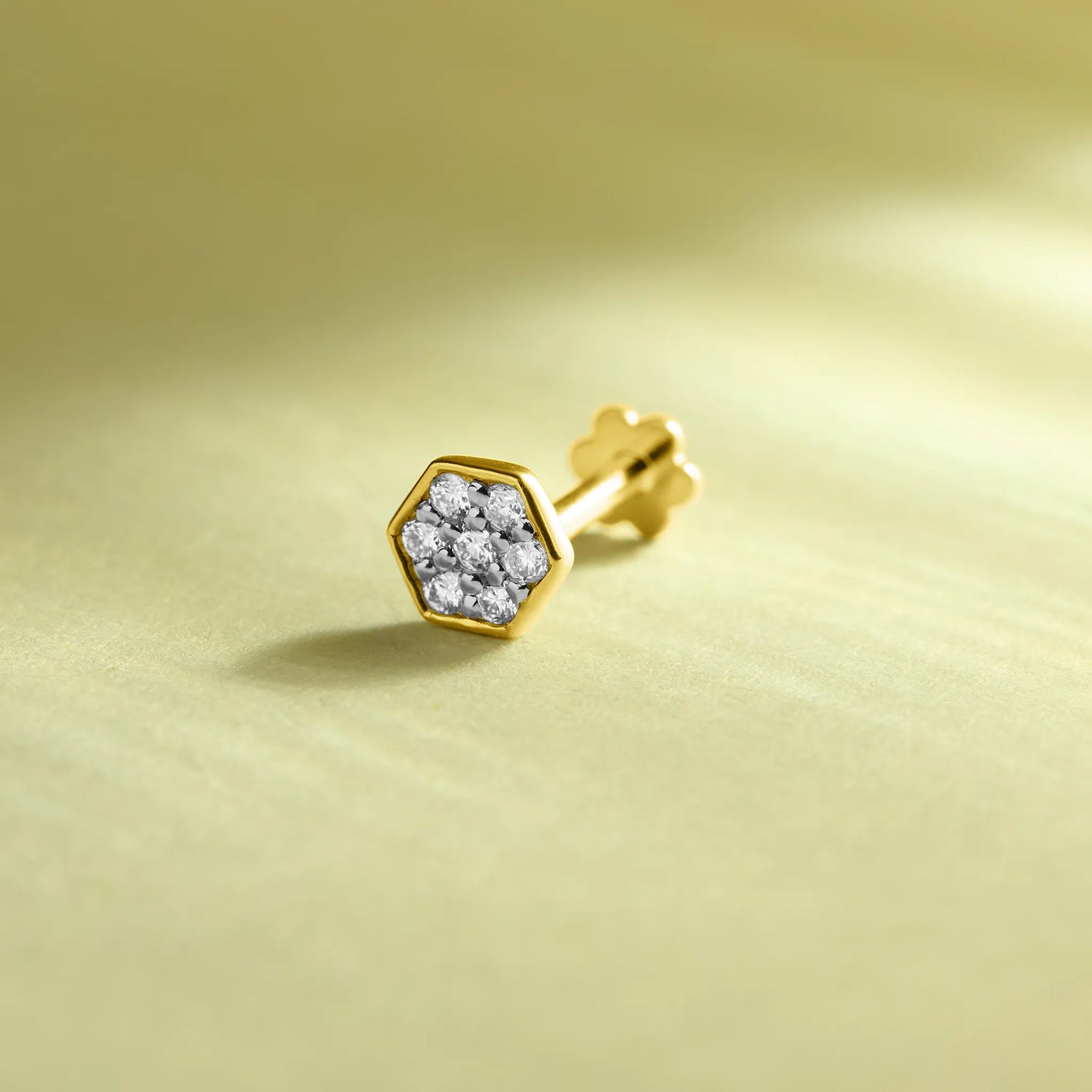 Gold hexagon diamond nose pin on soft pastel background