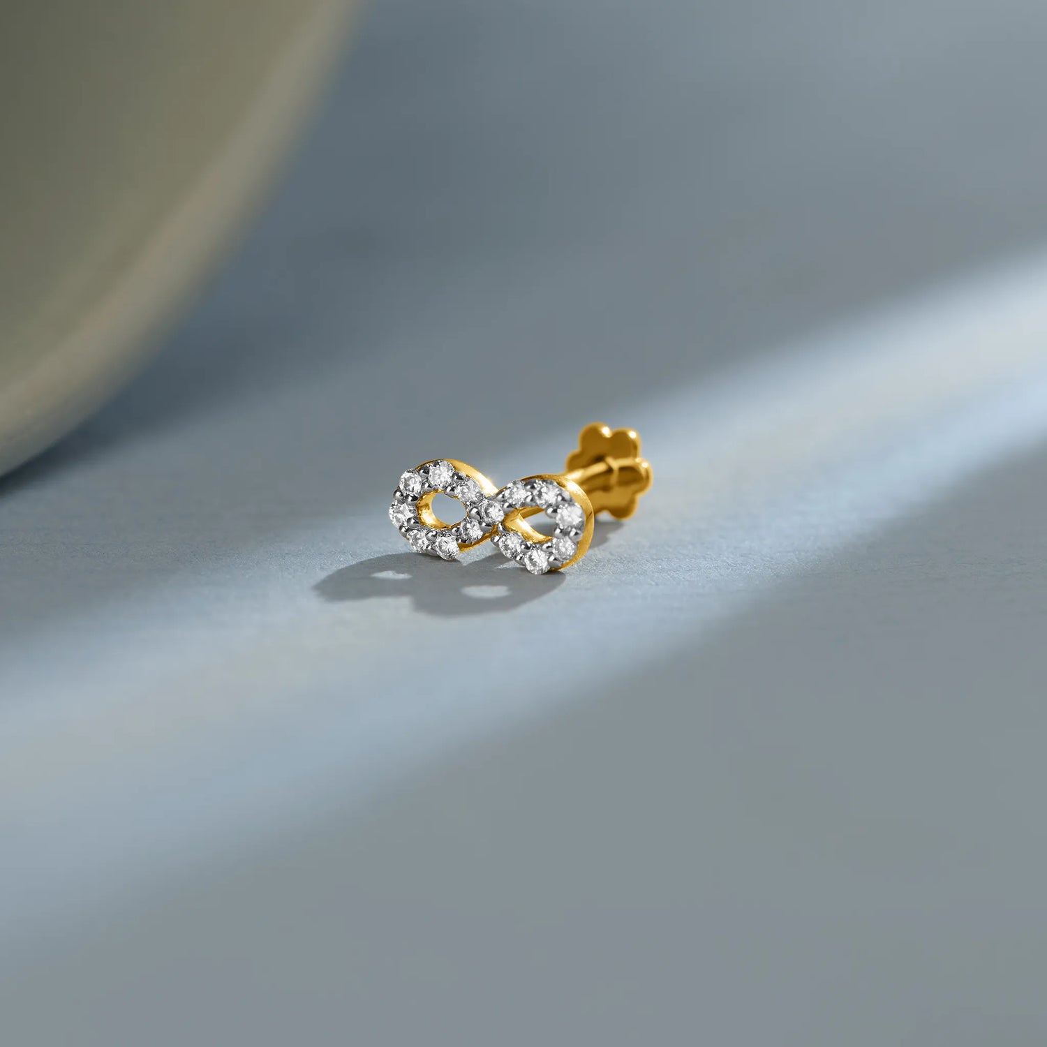 New nose pin design gold with elegant twin floral stone pattern set in a polished gold base on a soft pastel background