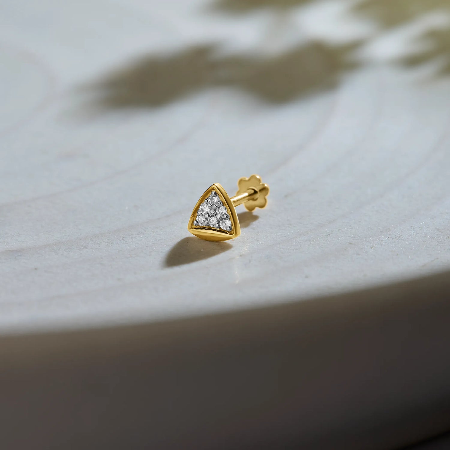 Gold triangle diamond nose pin on soft textured background