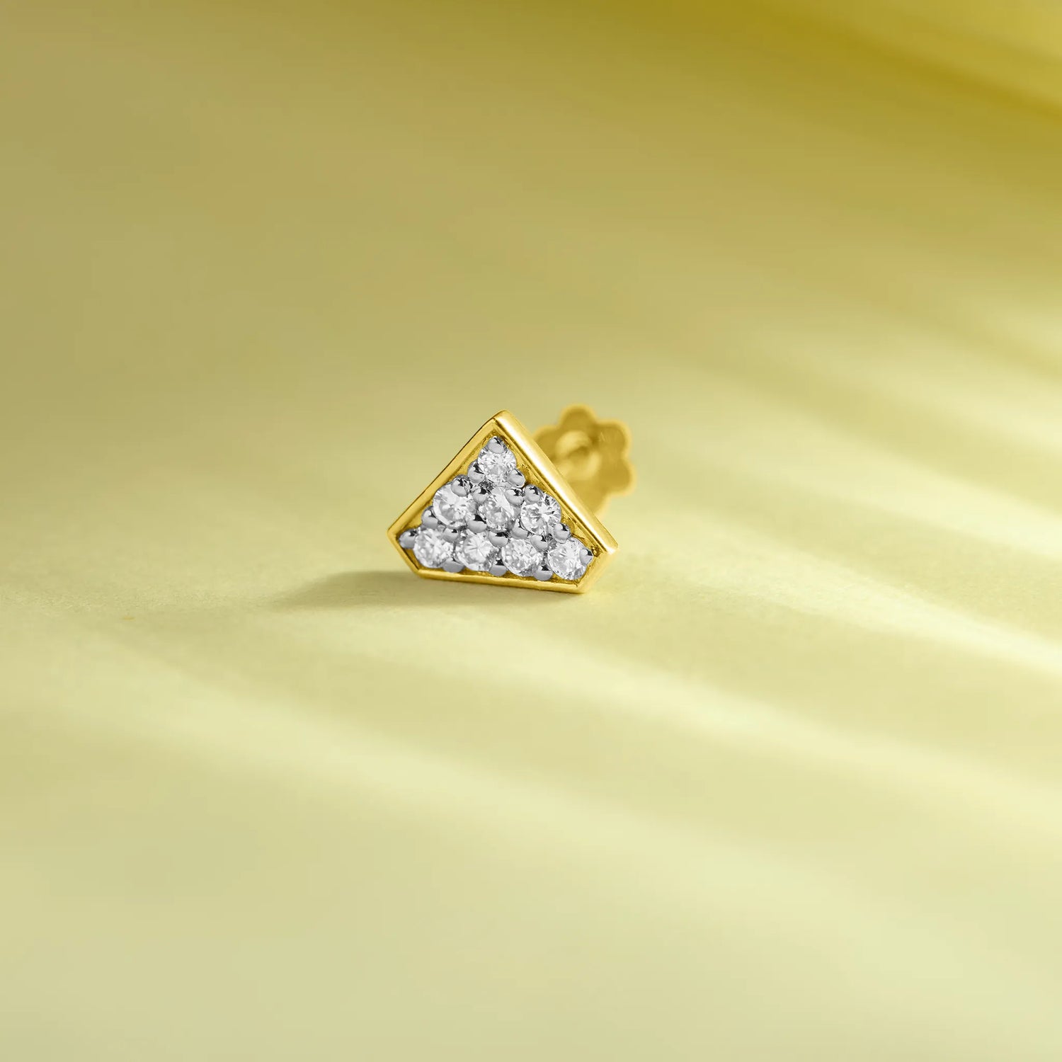 Gold triangle diamond nose pin product image on pastel yellow background