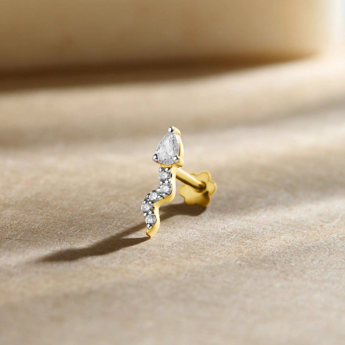 Diamond second stud price gold nose pin with pear shaped diamond and curved design on soft background