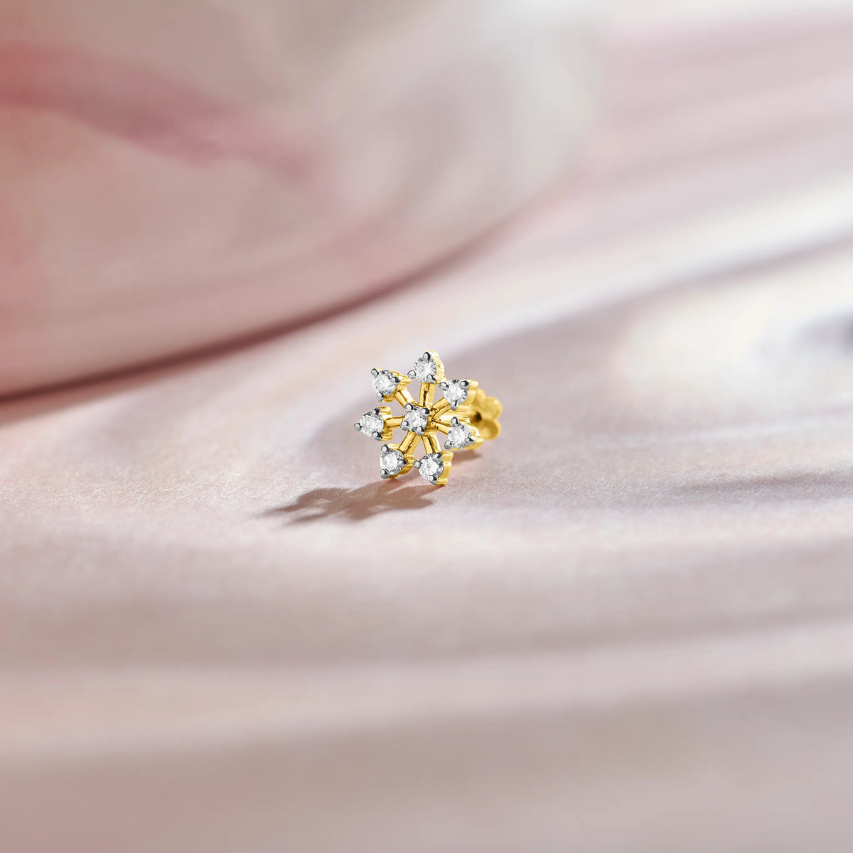 Diamond star shape design 18K gold nose pin with sparkling diamonds on soft pastel background