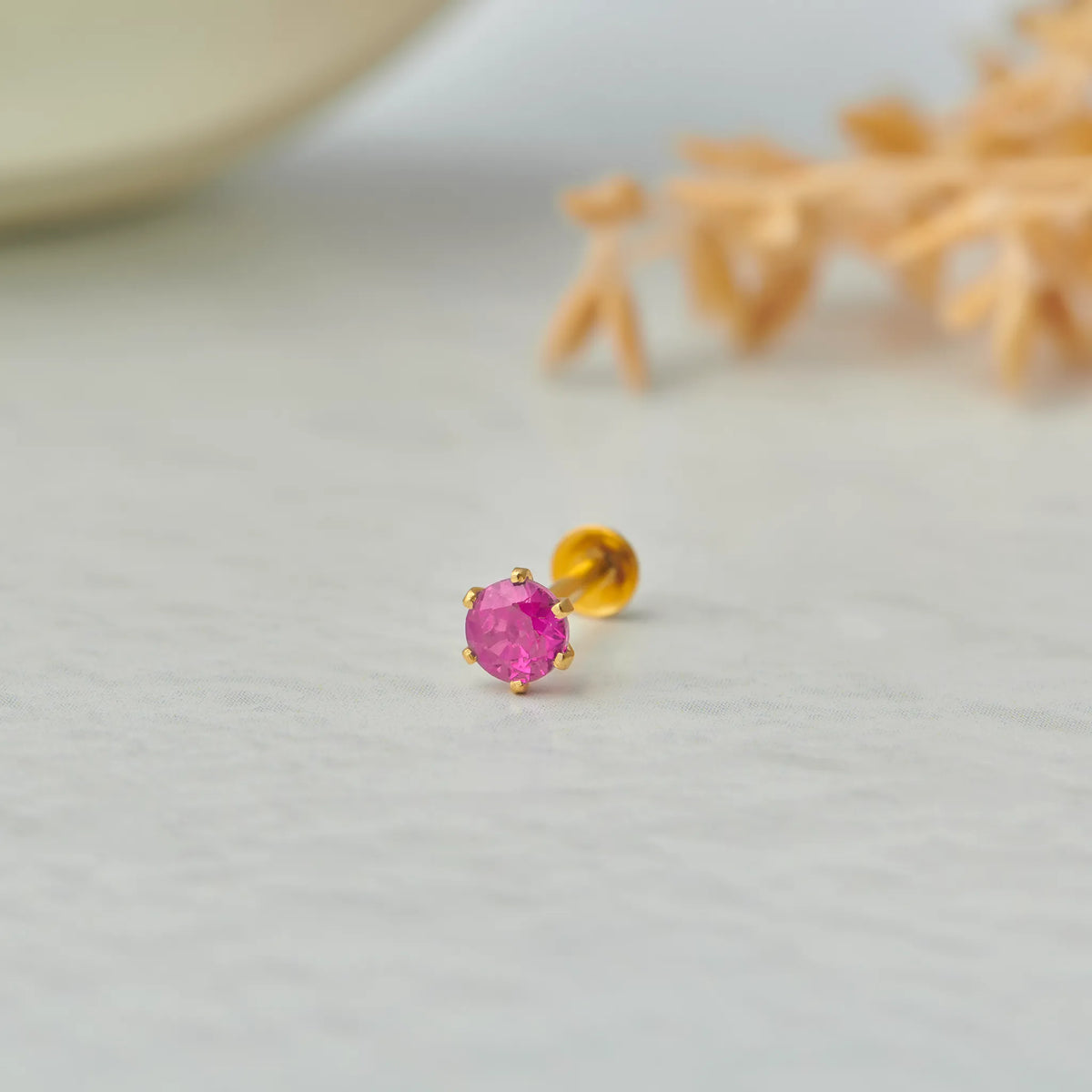 Close up of single ruby stone gold nose pin on white background