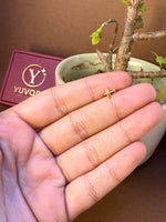 Alternate view of simple cross-shaped gold nose pin, held in hand
