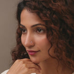 Gold nose pin worn on the nose in a close-up portrait, showcasing a minimal and sophisticated everyday jewelry look