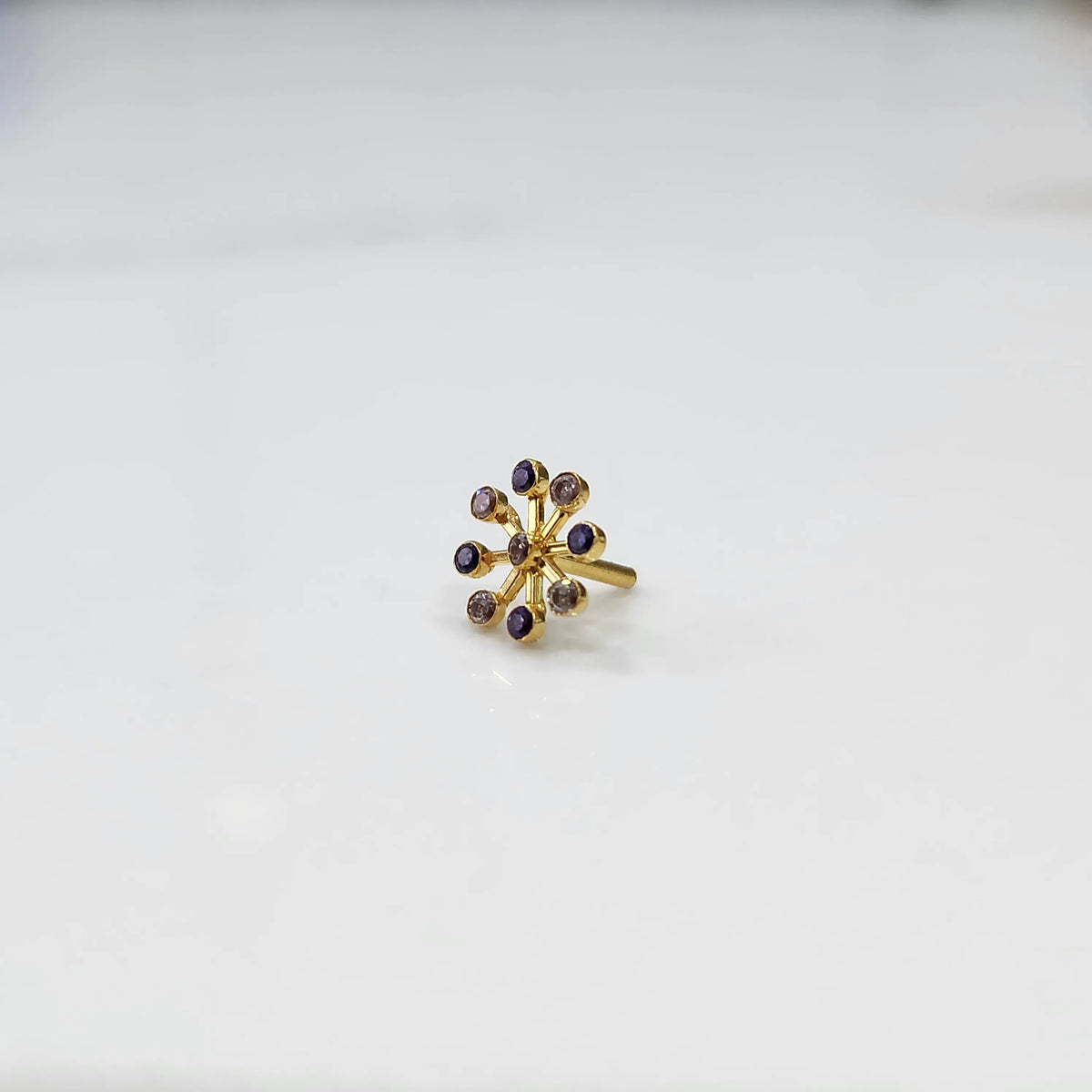 Product shot of a gold flower ring with nine amethyst stones