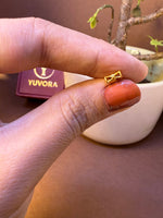 Small bow-shaped gold nose pin, held between fingertips
