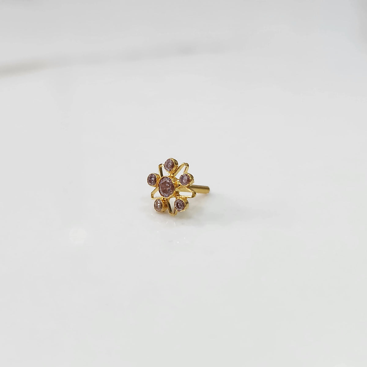A gold nose pin shaped like a star, set entirely with soft pink-brown crystal stones
