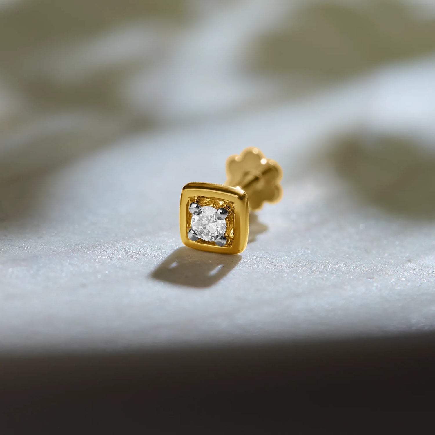 Simple gold square nose pin design with diamond on soft background