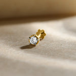 Diamond nose pin design from Kerala in gold with a classic solitaire diamond setting in a polished gold base on a soft neutral background